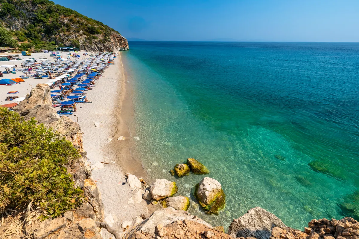 A Gjipe-strand napernyőkkel és strandolókkal.