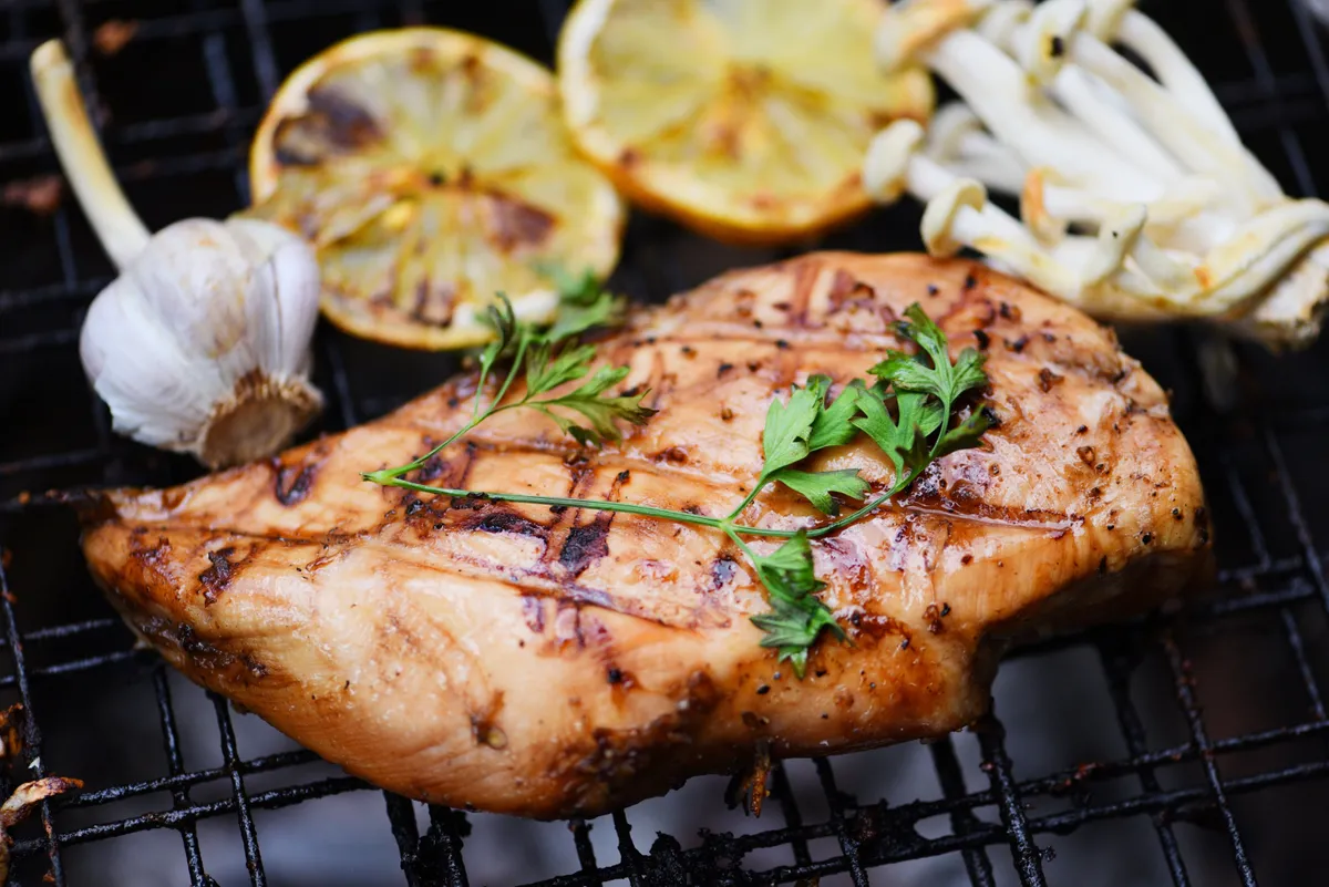 Csirkemell és más diétás grillételek sülnek a rácson.