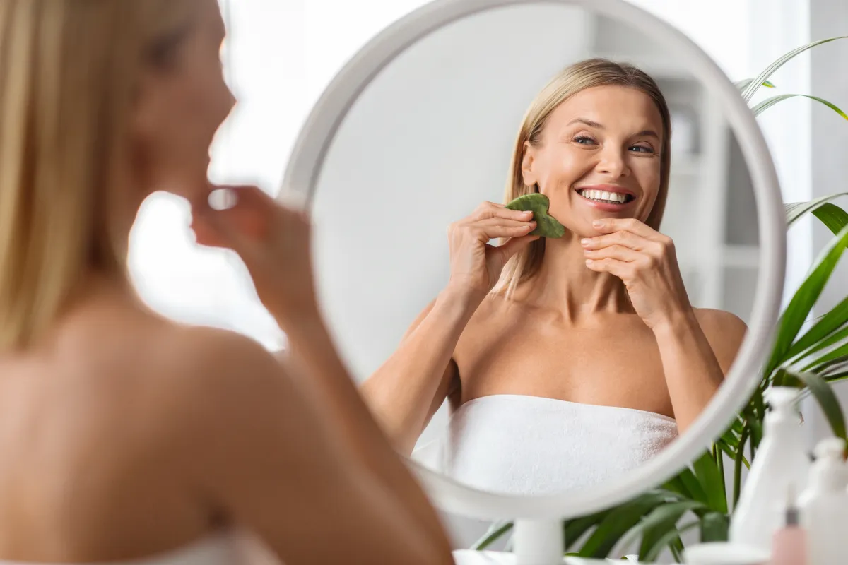 A ráncok ellen Gua Sha arcmasszázst alkalmazó nő.