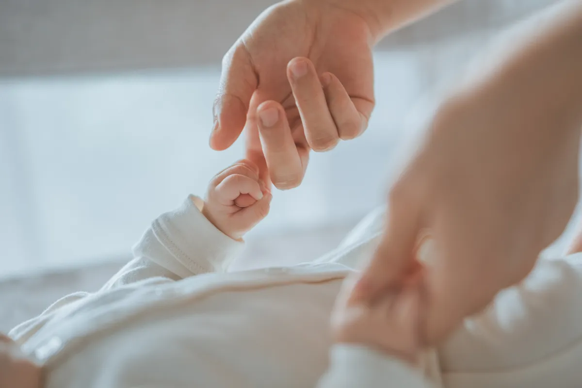 A horoszkóp alapján szerencsés anyuka kezét fogja a kisbabája.