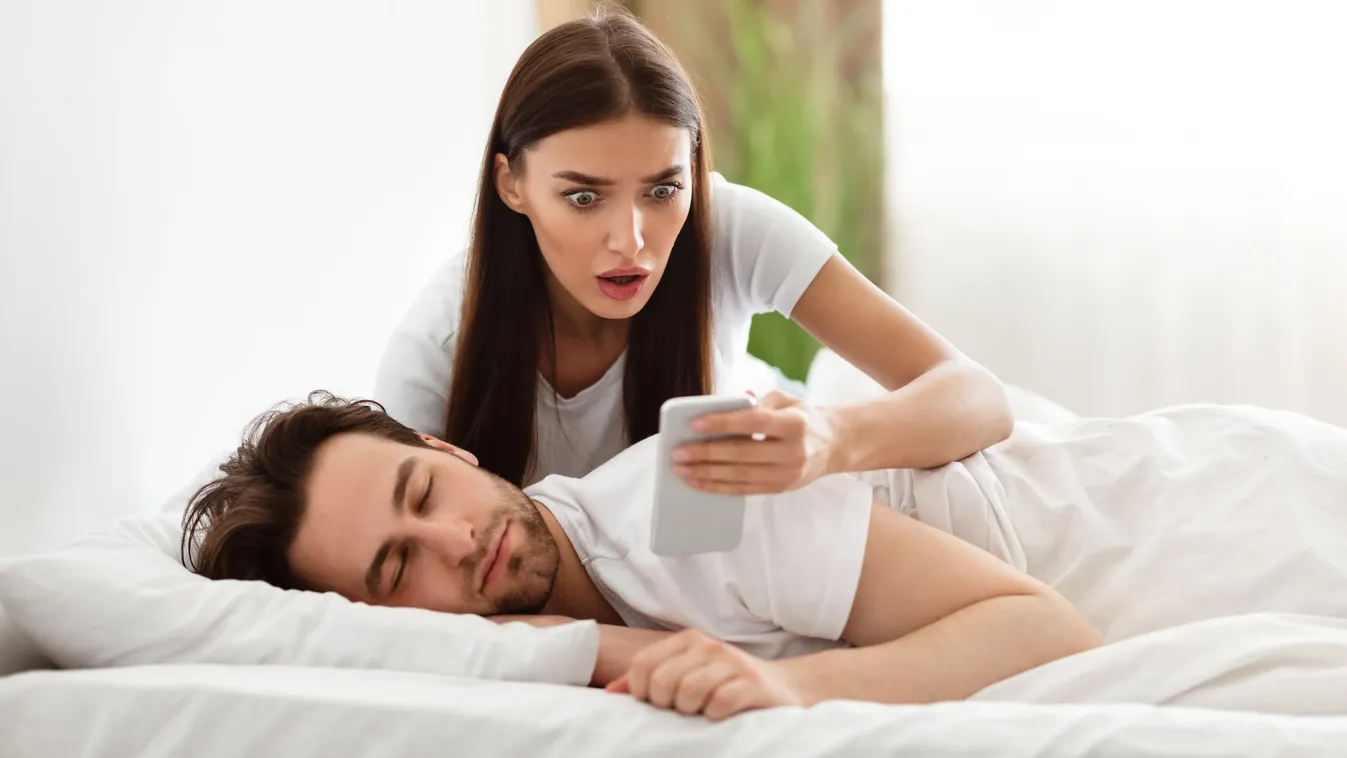 Egy nő döbbenten nézi meg párja telefonját, akit megcsal a férje.