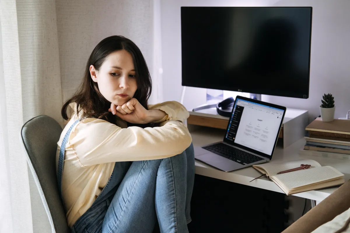 Thoughtful,Woman,Sitting,By,A,Desk,With,Laptop,With,Chatgpt.