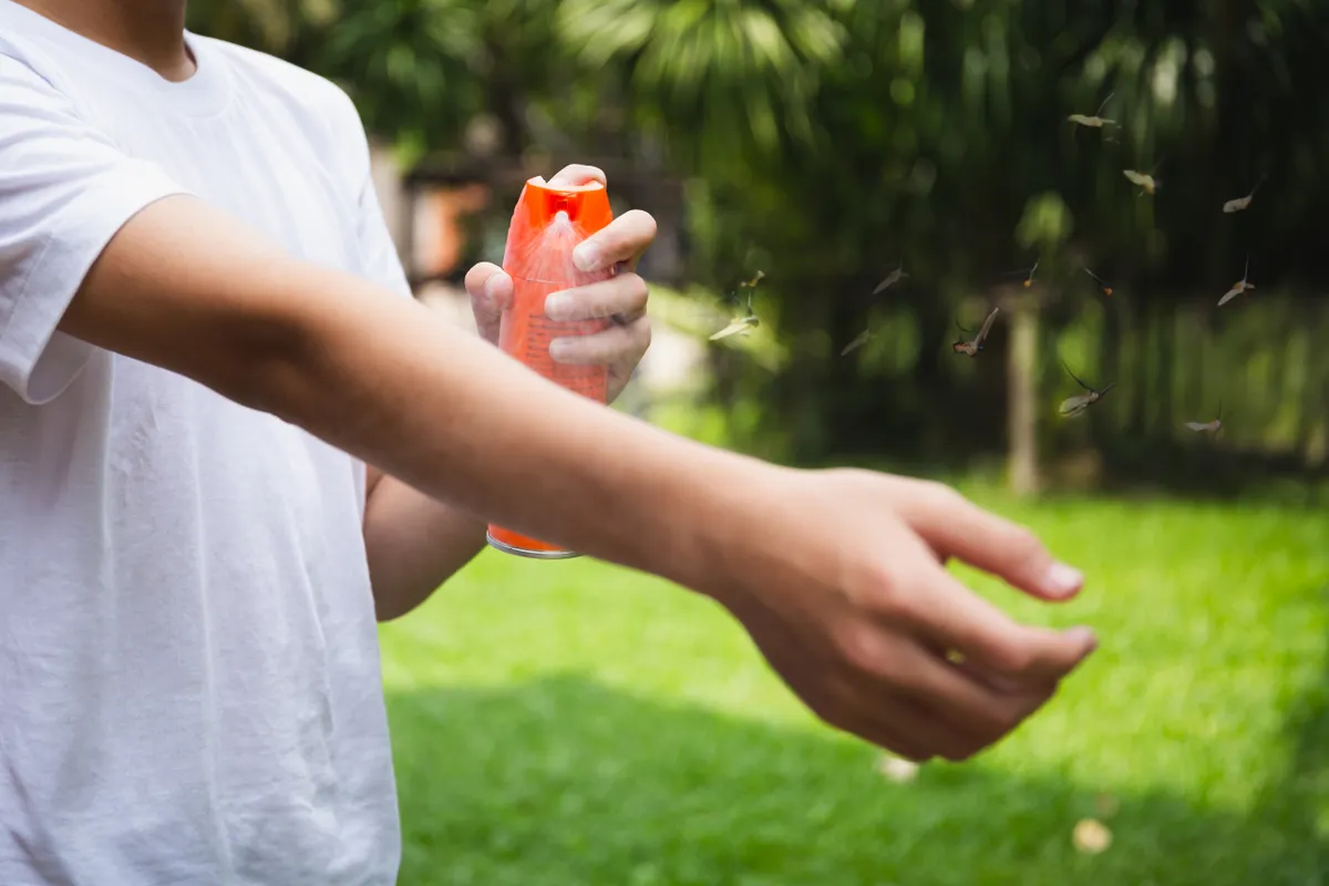 Szúnyog elleni sprayt fúj a karjára fiatal fiú