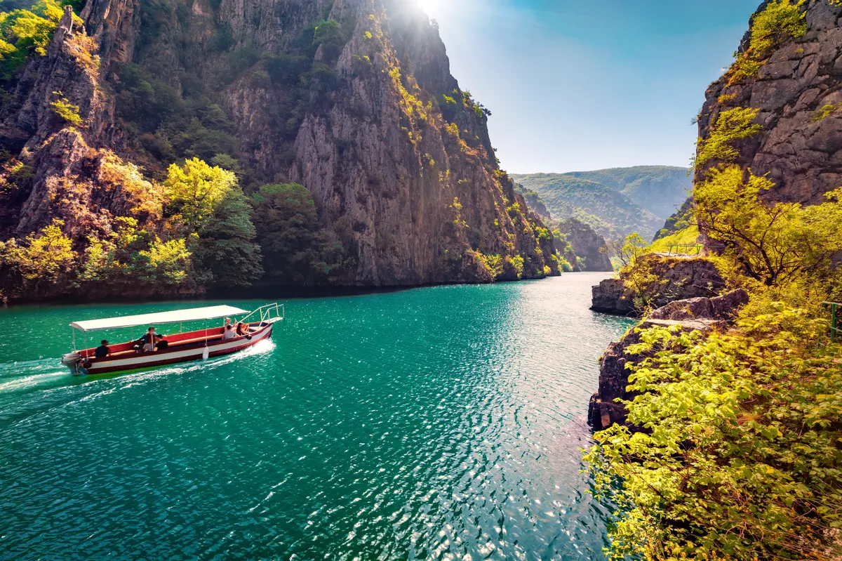 Az észak-macedóniai Matka-kanyon kis hajóval napsütésben.