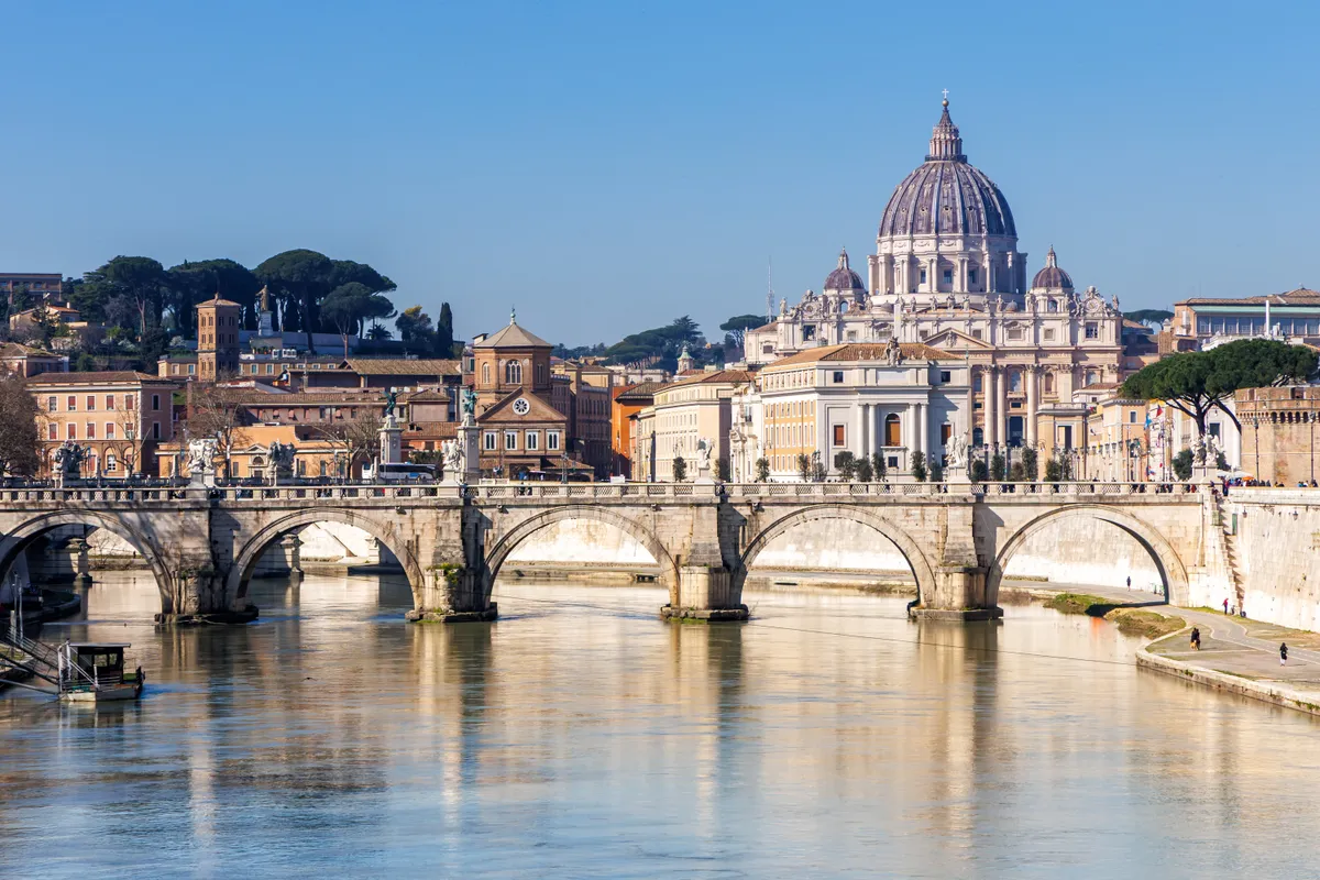 Róma a Tevere-folyóval és a vatikáni Szent Péter-bazilika tömbjével, illetve az egyik híddal.