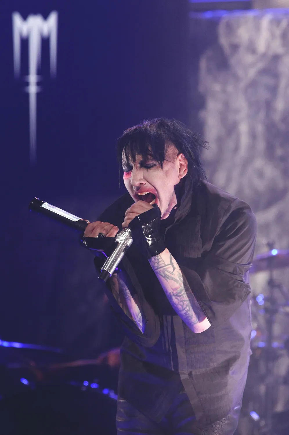 Marilyn Manson fehérre alapozott arccal, erős sminkben üvolt a mikrofonba.