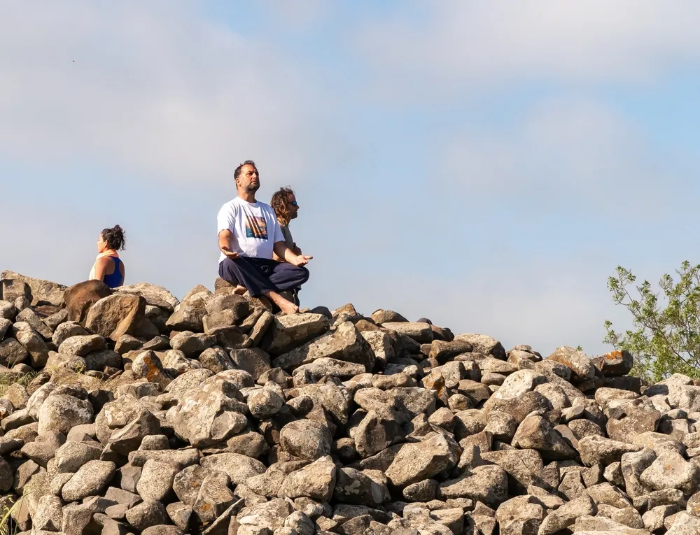 Középkorú férfi sziklán meditál 