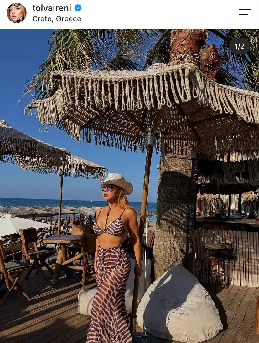 Tolva Reni állatmintás strandruhában és kalapban pózol a parton.