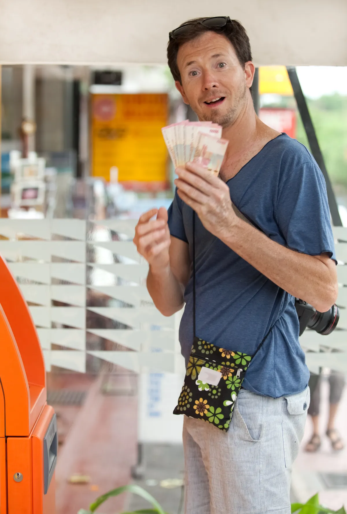 Fiatal férfi pénzt vesz fel egy automatánál. 