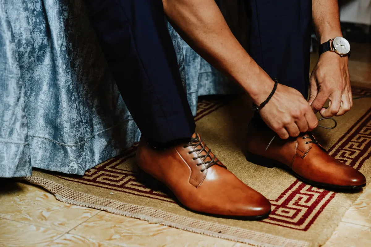 Closeup shot of a young male tying his luxurious brown shoes