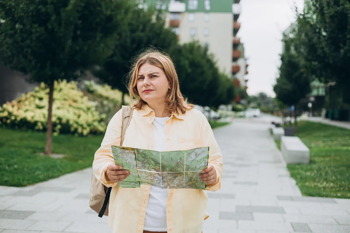 Papírtérképet a kezében tartó női turista. 