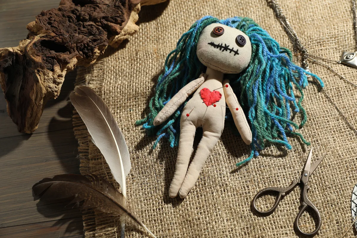 Kék hosszú hajú voodoo baba gombostűkkel a testében. 