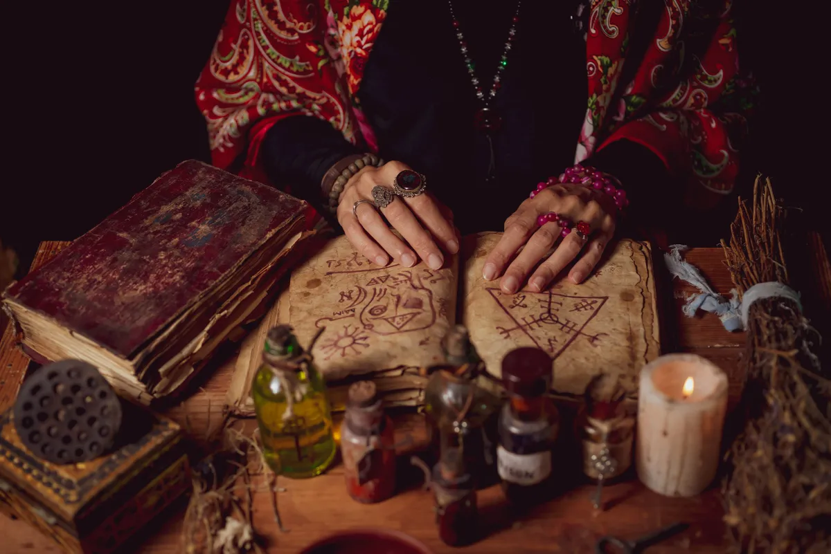 Mágikus szeánsz egy varázsigéket és rituálékat tartalmazó könyvvel és bájitalokkal, gyertyákkal