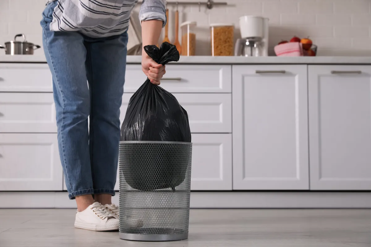 Szemeteszsák kiemelése a kuka közepéből