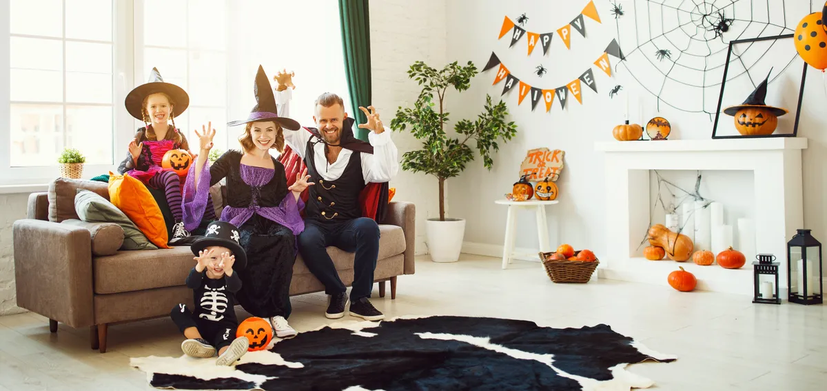 Egy család tagjai különféle halloween jelmezekben a nappali szobában